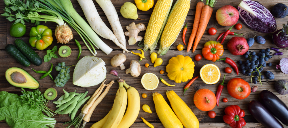 view from above of various fruits and vegetables arranged on a wooden table